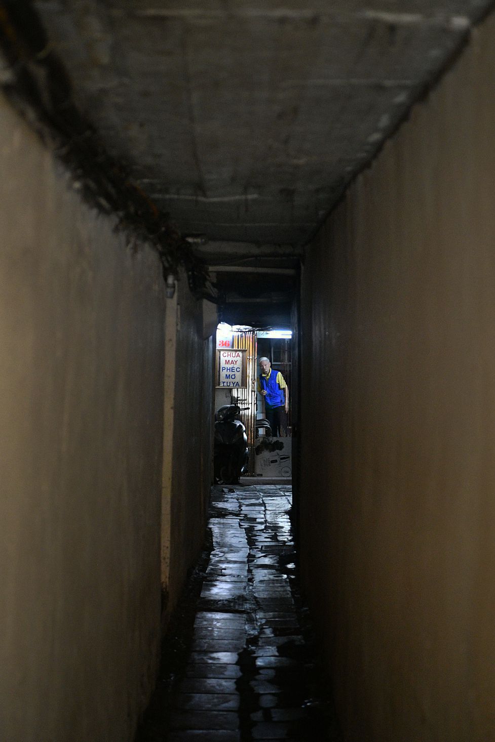 Hình ảnh cụ già ở cuối ngõ với tấm biển “Chữa may Phéc mơ tuya” tạo cảm giác về một không gian sống vẫn giữ được những nét nghề dân sinh truyền thống. Ảnh: Việt Văn