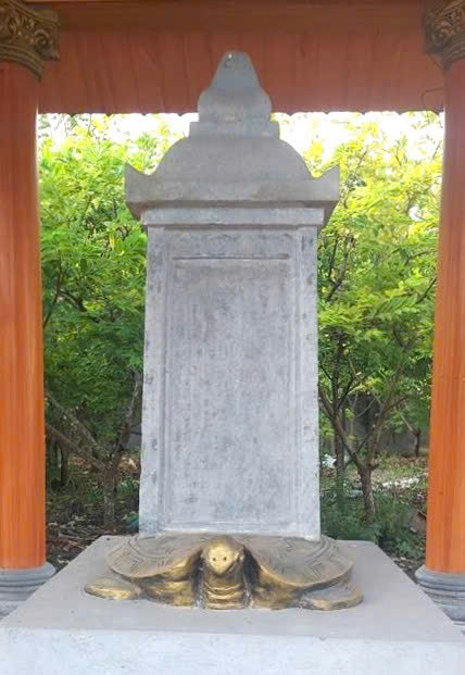 Tấm bia cổ được lưu giữ trong khuôn viên đền Quảng Cư. Ảnh: Thanh Tâm 