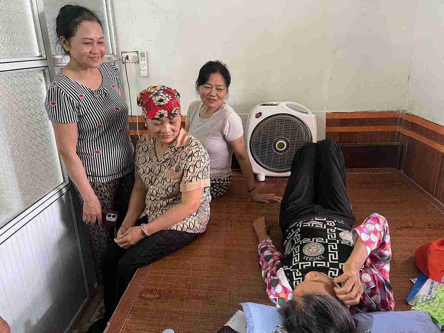 Neighbors took the opportunity to visit and encourage Mrs. Net who had just returned from dialysis. Photo: Mai Huong