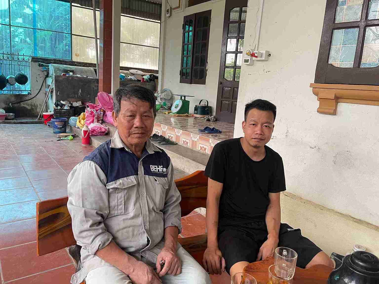 Ông Đặng Văn Thẩm ngồi cạnh con trai sau một ngày đi phụ hồ trở về nhà, gương mặt mệt mỏi, lo toan. Ảnh: Mai Hương