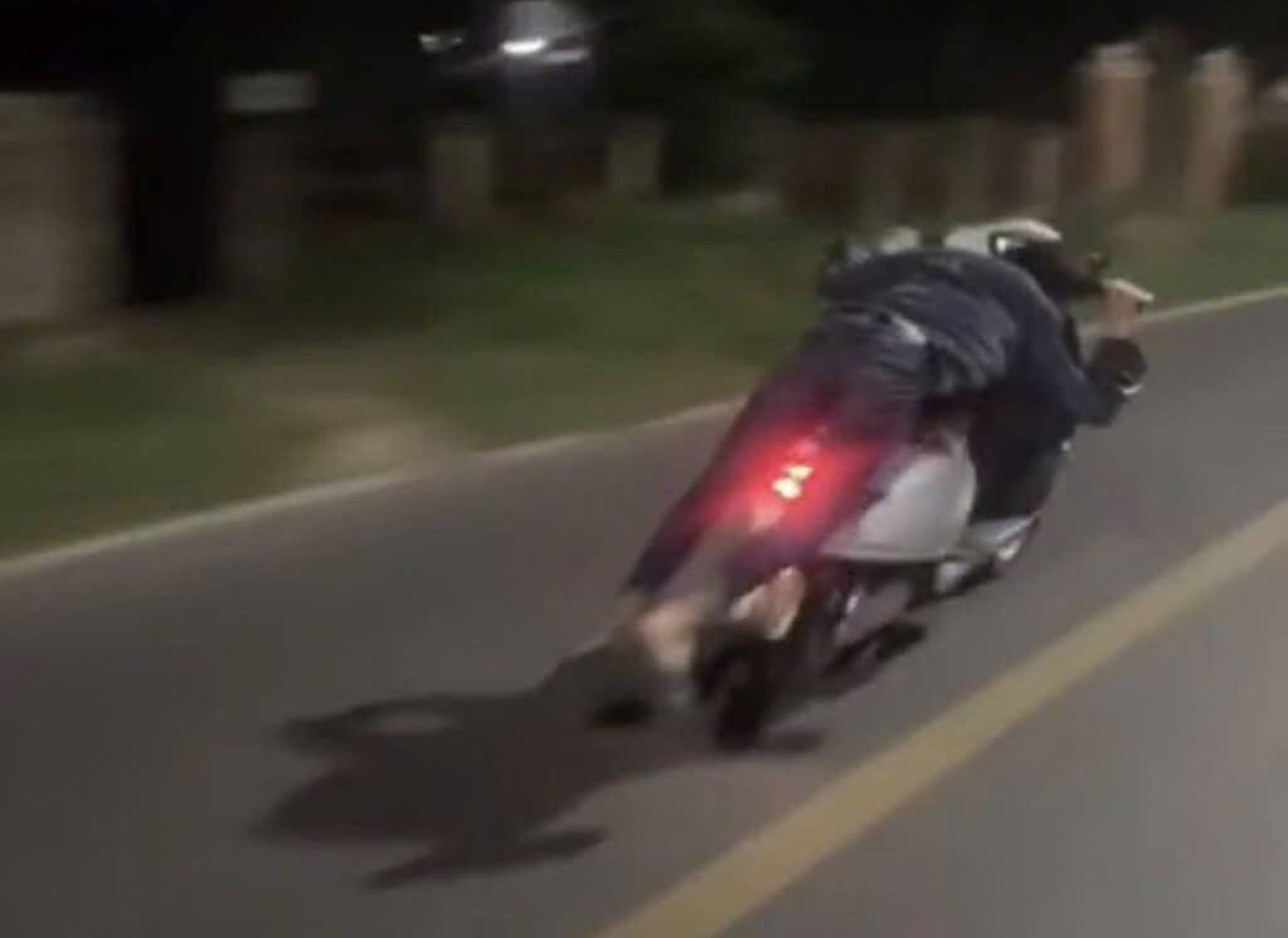 Male student lying on the seat of an electric motorbike while driving was just handled by traffic police forces. Photo: People provided