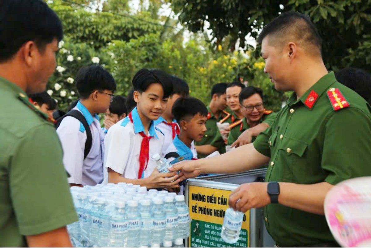 Học sinh phấn khởi nhận nước suối và bánh mì từ các anh Công an. Ảnh: Công an Cần Thơ