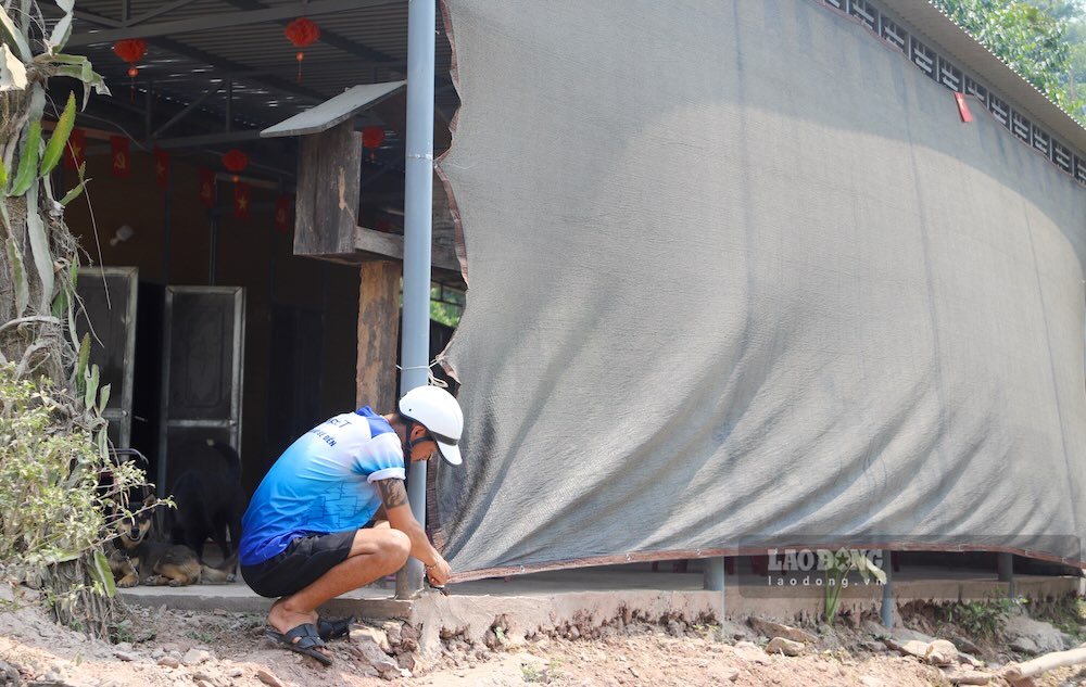 Anh Thành gia cố lại tấm bạt che bụi tại khu vực quán ăn của gia đình. Ảnh: Nguyễn Luân