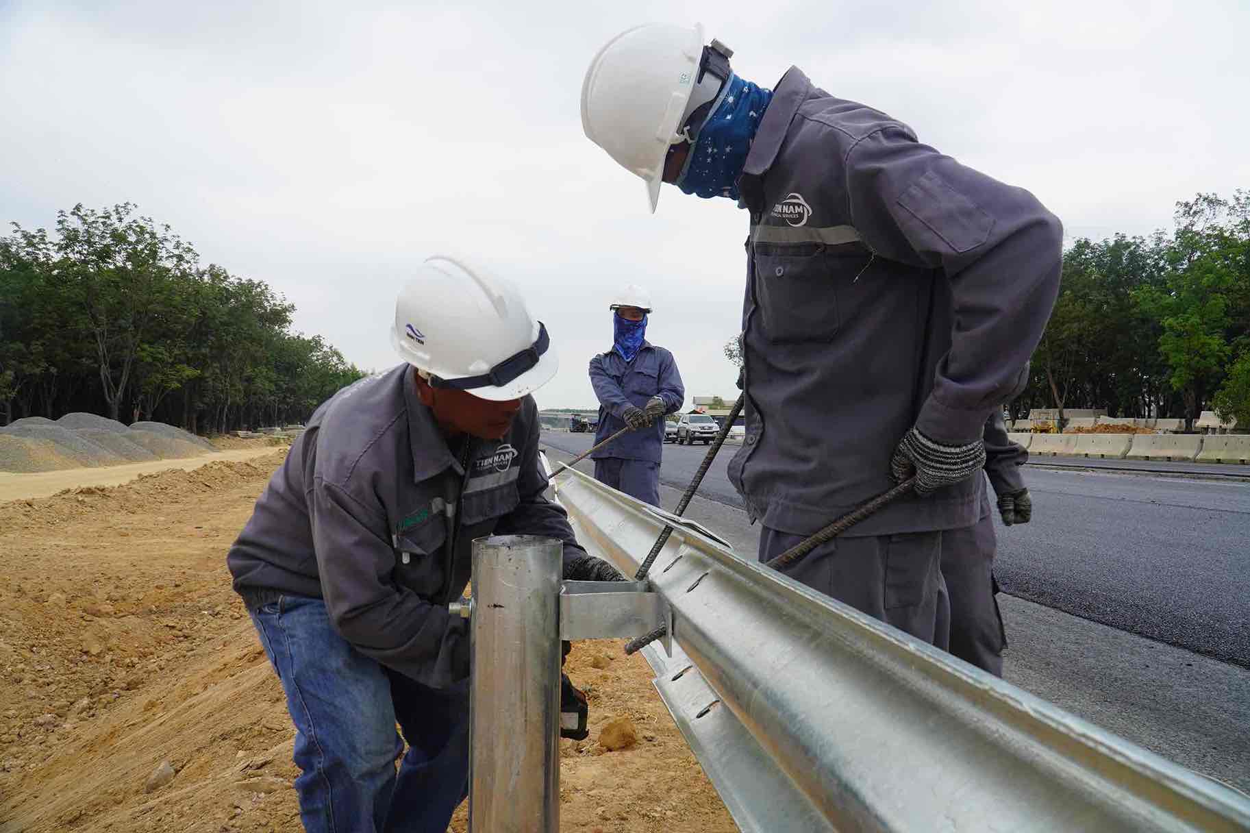 Lắp tôn hộ lan được công nhân thi công khẩn trương, gấp rút kịp tiến độ. Ảnh: HAC