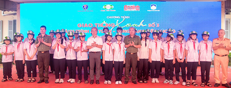 Tặng mũ bảo hiểm cho học sinh trong buổi tuyên truyền về an toàn giao thông. Ảnh: Ngọc Châu