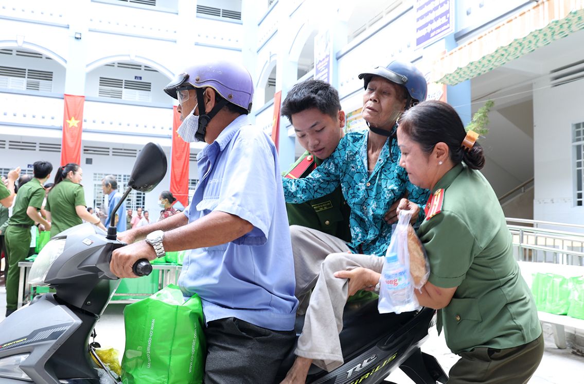 Không chỉ tặng quà, đoàn công tác thiện nguyện còn ân cần chăm chút từng bước đi cho người cao tuổi, qua đó tạo được dấu ấn nhân văn trong lòng người dân. Ảnh: Vũ Tiến