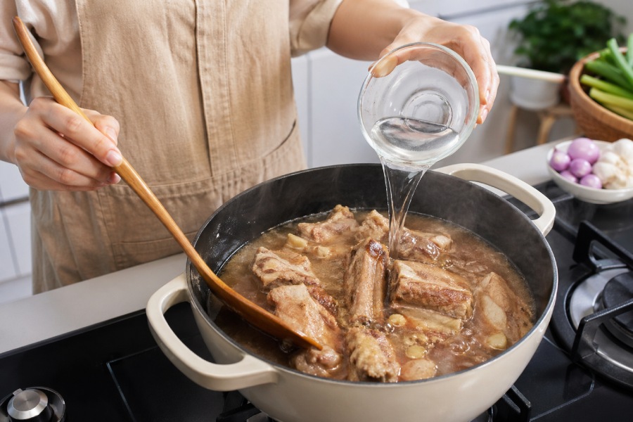 Sườn non được đảo săn trên bếp trước khi thêm nước dừa hoặc nước lọc để kho mềm. Ảnh: Thùy Linh 