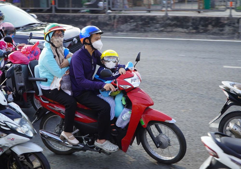 Trên các xe máy, hình ảnh cha mẹ chở theo con nhỏ, thậm chí bồng bế trẻ em giữa dòng xe đông đúc khá phổ biến.