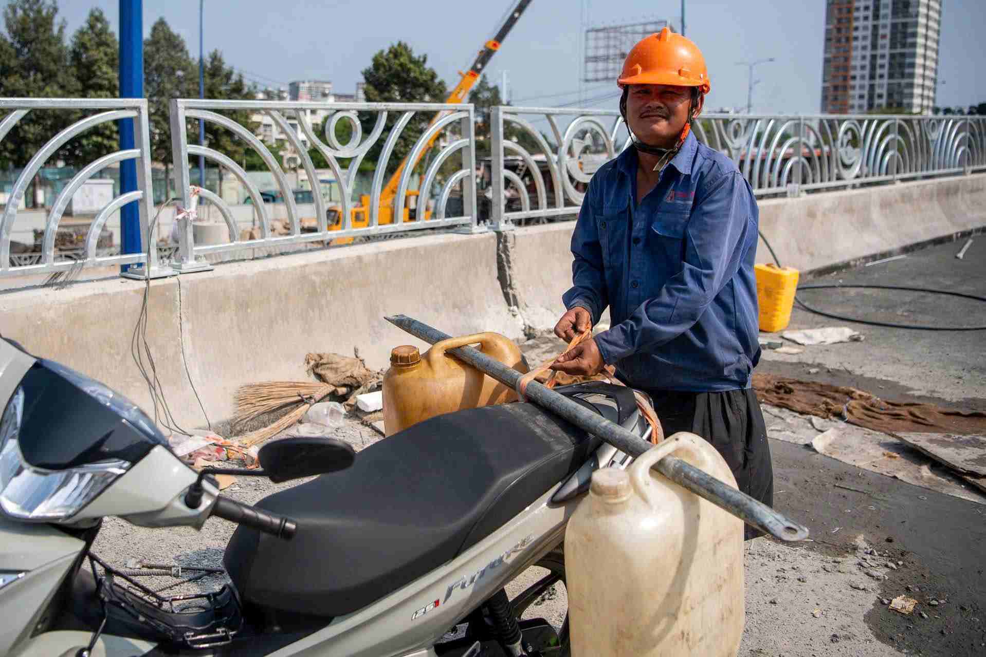 Người đàn ông chở nước lên để xịt lan can và rửa đường chuẩn bị thông xe nhánh cầu N3 ngày mai (1.5). Ảnh: Anh Tú