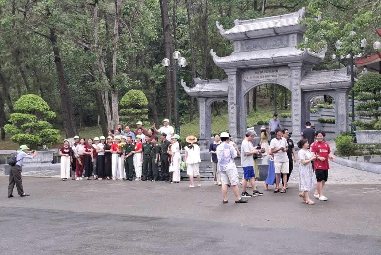 Nhiều người chụp hình lưu niệm trước cổng Nhà bia tưởng niệm liệt sĩ thanh niên xung phong toàn quốc. Ảnh: Trần Tuấn