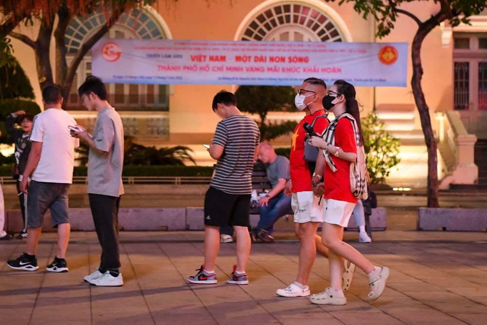 Người dân diện áo cờ đỏ sao vàng đến khu vực trung tâm TPHCM chờ xem pháo hoa. Ảnh: Thái Bảo