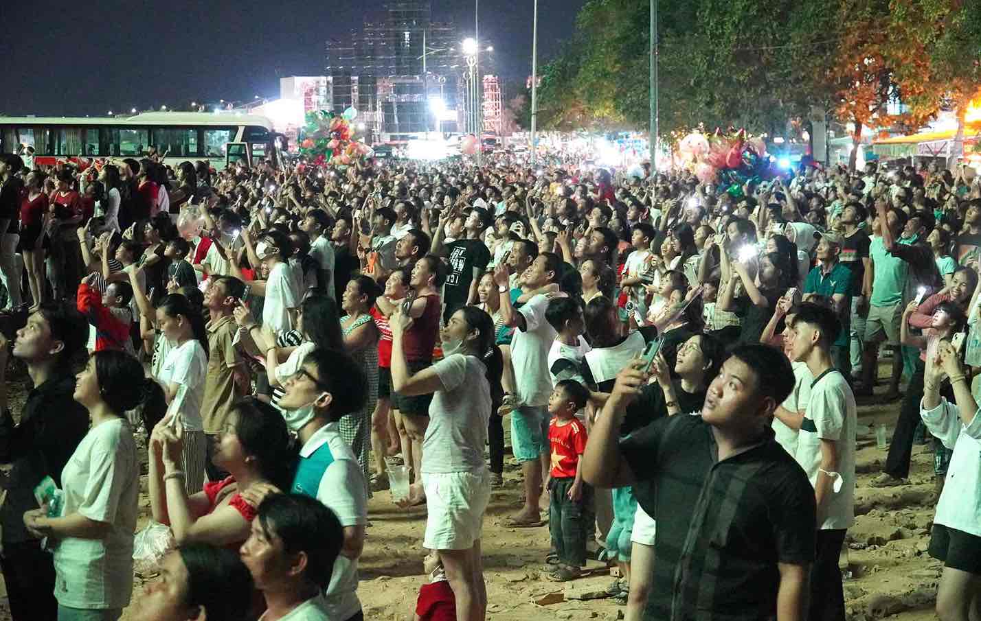 Người dân đứng tại đoạn đường ven sông Đồng Nai xem bắn pháo hoa. Ảnh: HAC