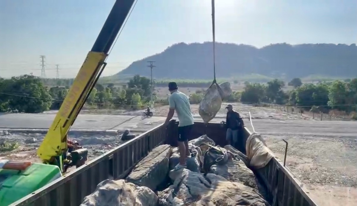 Xe cẩu hạ tải trọng hàng hóa trên thùng xe đầu kéo. Ảnh: Phạm Duy 