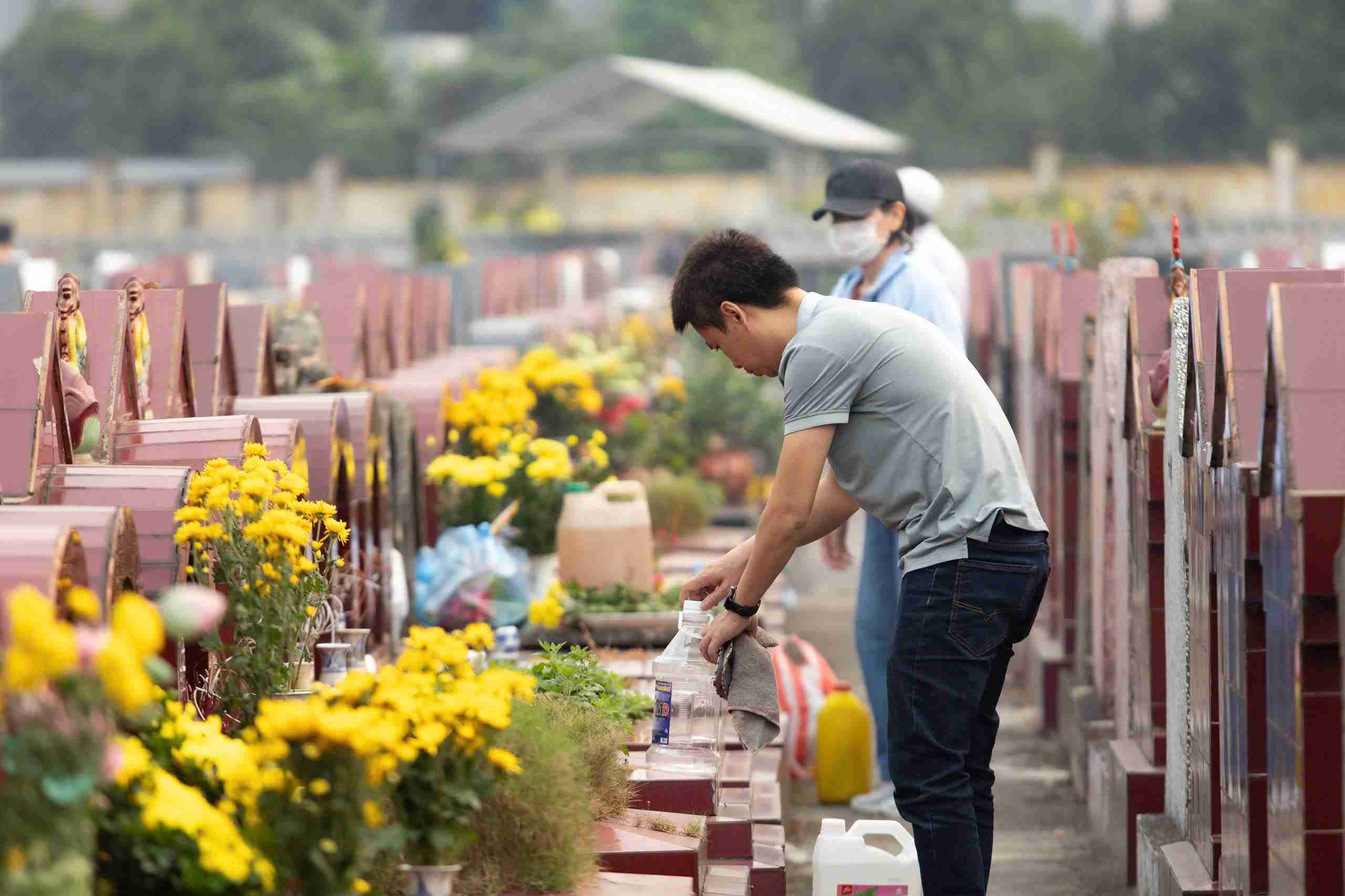 Las familias están ocupadas limpiando, desbrozando y cuidando las tumbas ancestrales. Foto: Mai Huong