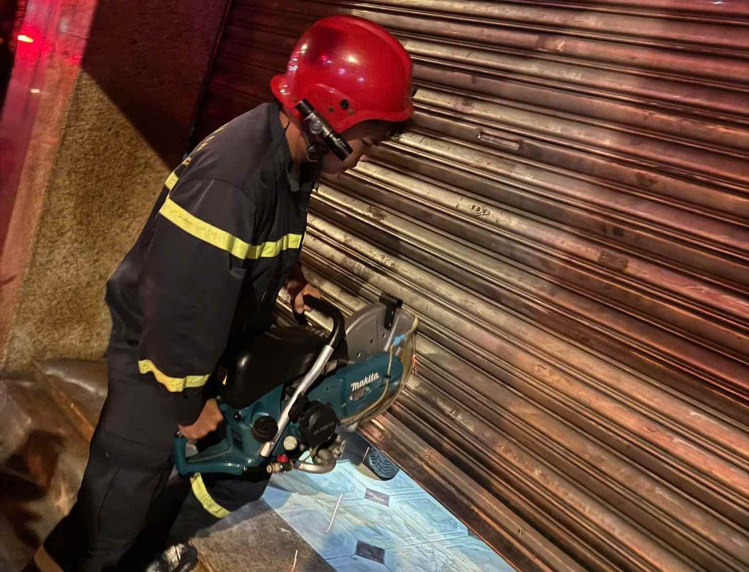 Lực lượng chữa cháy tìm cách tiếp cận vào bên trong để cứu người bị nạn. Ảnh: phường Chợ Quán