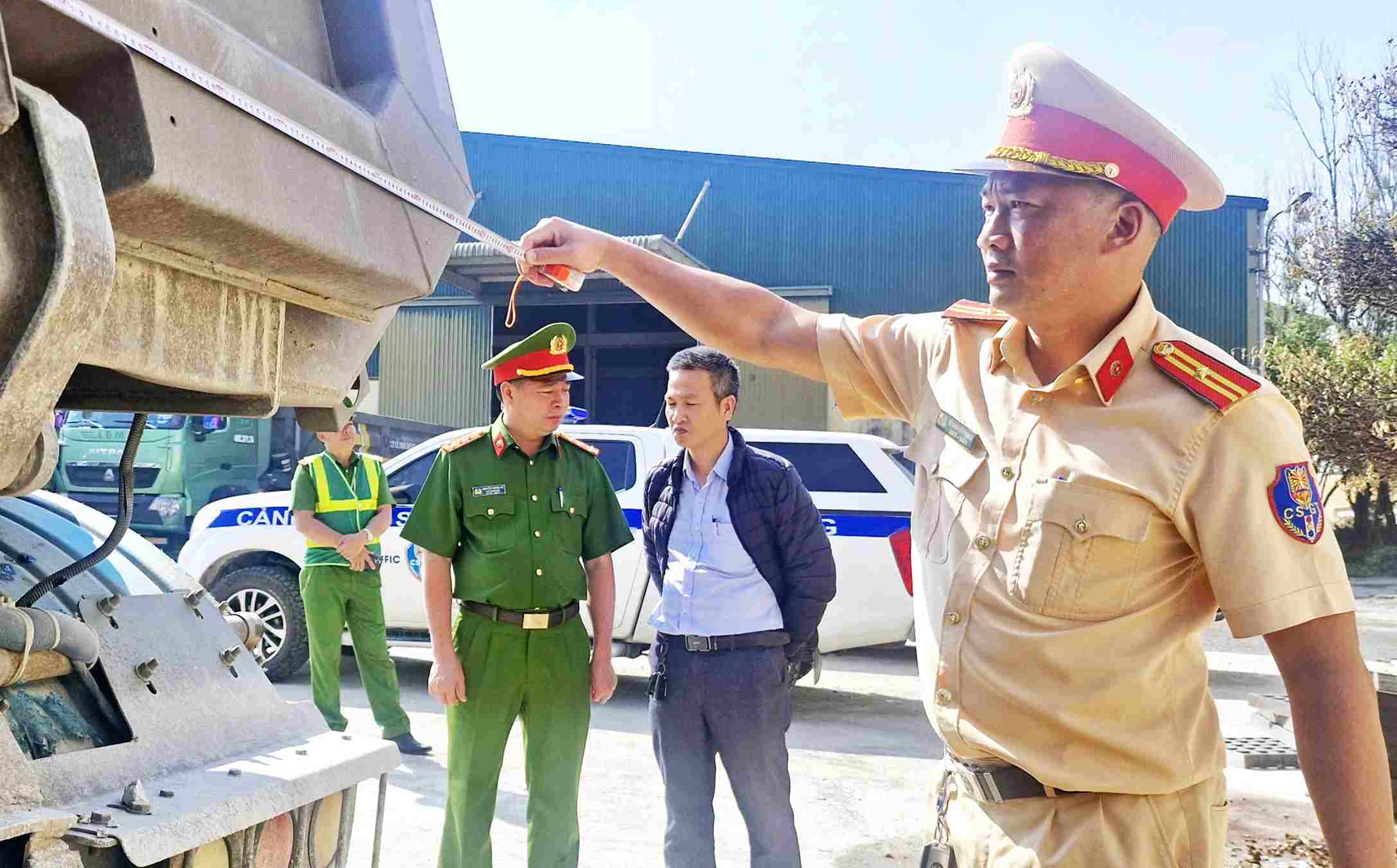 Lực lượng CSGT kiểm tra, đo kích thước thành thùng xe ô tô tải tại doanh nghiệp. Ảnh: Phúc Khánh 