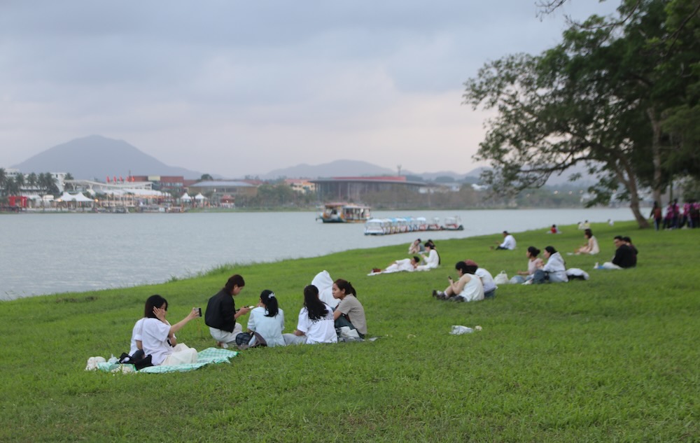 Tourists enjoy the cooling space on the banks of the Perfume River. Photo: Ngo Hien
