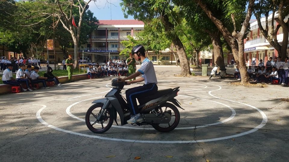 Học sinh lớp 12 Trường THPT Trà Ôn thực hành bài thi liên hoàn vòng số 8, nâng cao kỹ năng lái xe an toàn dưới sự hướng dẫn của công an xã. Ảnh: Hoàng Lộc