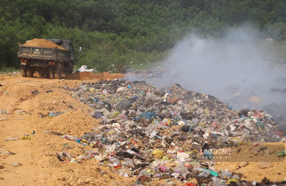 Xe tải chở đất lấp vào bãi rác đang bốc cháy âm ỉ. Ảnh: Nguyễn Luân