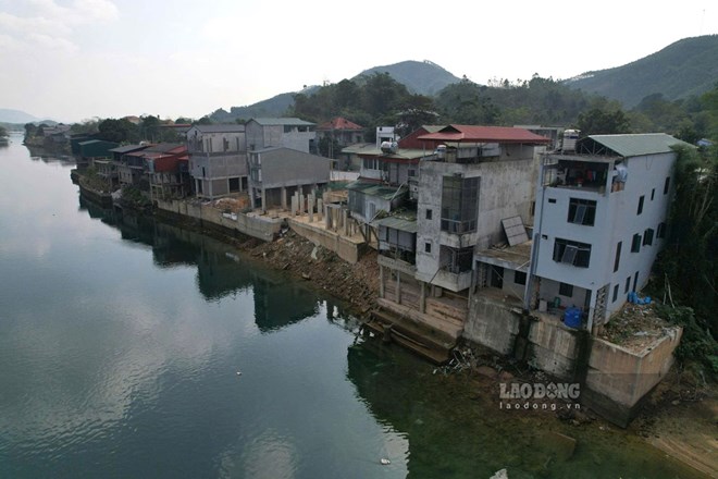 Những ngôi nhà nằm sát bờ sông tại xã Thác Bà bị xói mòn, nguy cơ sạt trượt luôn rình rập. Ảnh: Văn Đức. 