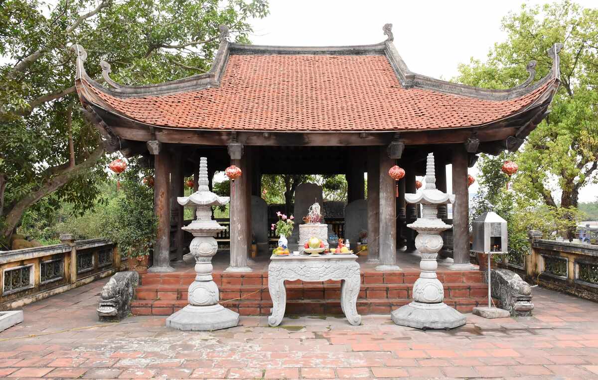 Nhà bia: Ở bên phải đền, được xây dựng tôn tạo cùng thời điểm với đền chính, quay hướng Đông, nền nhà bia cao 60cm, có ba bậc thềm lát gạch vuông phục chế, hai bên bậc thềm có đôi rồng chầu bằng đá xanh. Kiến trúc nhà bia theo kiểu phương đình, có bốn mái cong, lợp ngói mũi hài. Vì kèo kiểu giá chiêng chồng rường, con nhị, chạm khắc hoa văn uốn lượn. Lan can chấn song con tiện. Tất cả được làm bằng gỗ lim với tổng số 16 cột gỗ. Ảnh: Nguyễn Huệ