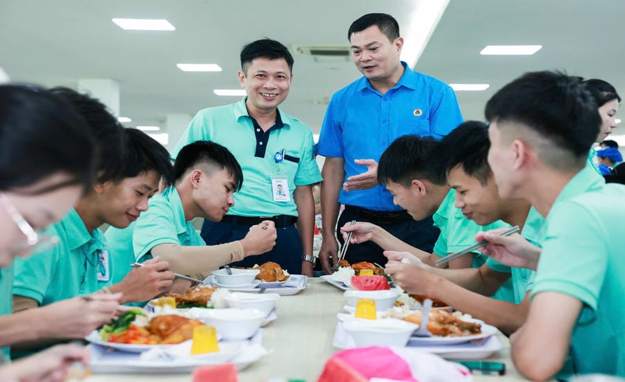 Mr. Nguyen Anh Ngoc - Chairman of the Trade Union of Canon Vietnam Co., Ltd. (standing on the right) - visits and encourages company workers at the 2025 Trade Union Meal organized by the company's Trade Union. Photo: Hai Nguyen
