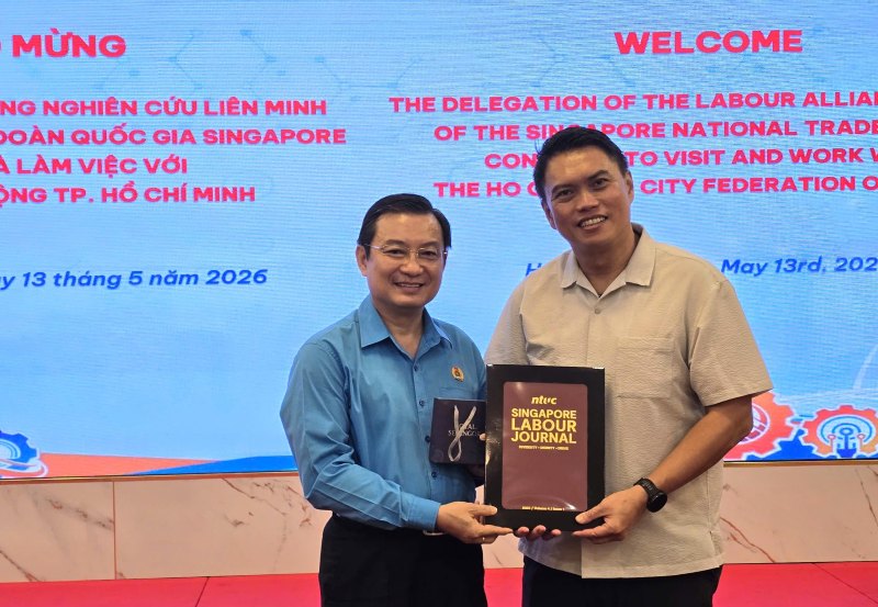 Mr. Patrick Tay - Assistant Secretary General of the Singapore National Trade Union (right) - presents souvenirs to representatives of the Ho Chi Minh City Labor Federation. Photo: Nam Duong