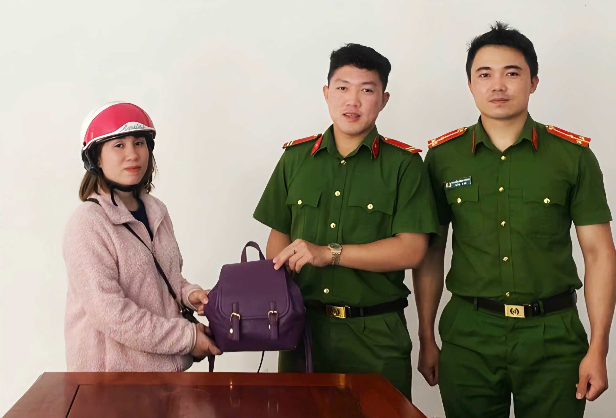 Soldier Tran Nhat Minh (center) returns the found property to Ms. Quyen. Photo: Police provided