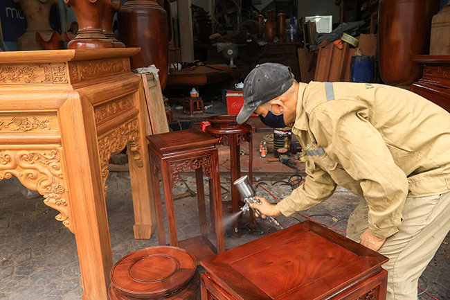 Người thợ tỉ mỉ sơn phủ bóng cho chiếc ghế trước khi xuất xưởng. Ảnh: Ngọc Huyền