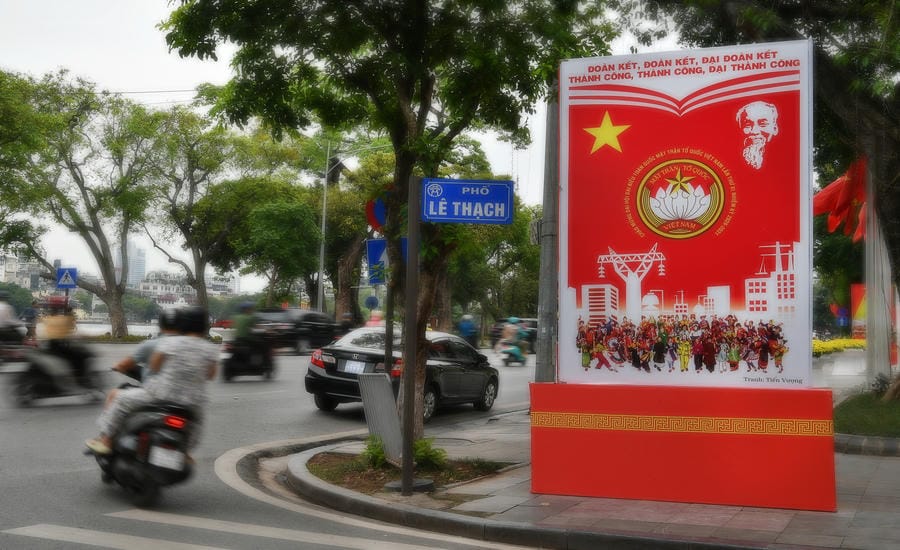 Một bảng cổ động với hình ảnh Chủ tịch Hồ Chí Minh được đặt bên Hồ Hoàn Kiếm, giữa dòng xe cộ và nhịp sinh hoạt thường nhật trên phố Lê Thạch, Hà Nội. Ảnh: Việt Văn