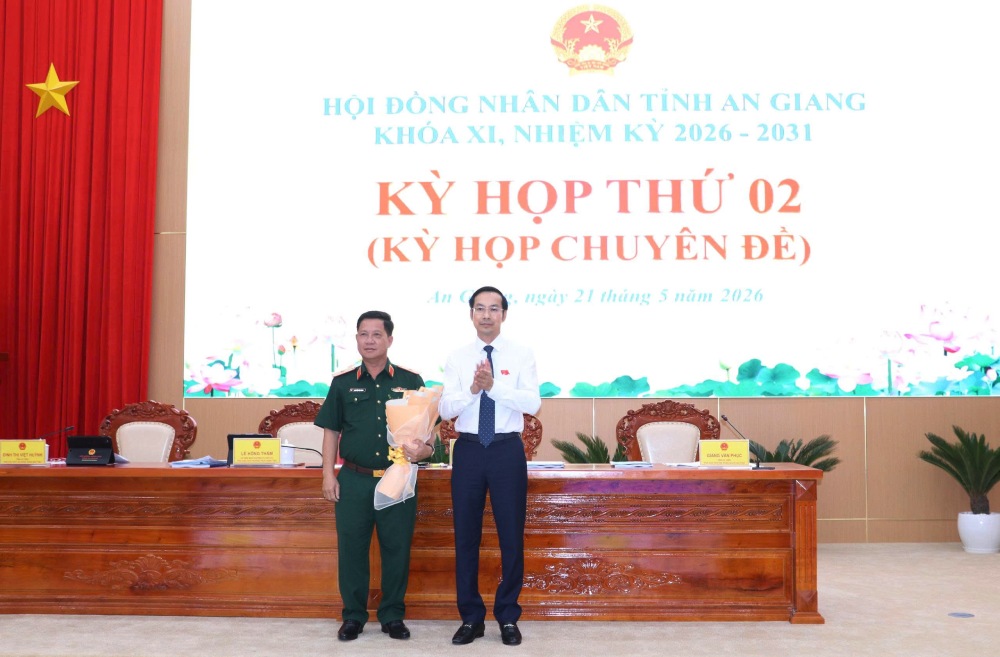 El Presidente del Consejo Popular Provincial de An Giang, Nguyen Thanh Nhan, entrega flores para felicitar al General de División Nguyen Van Hung - Comandante del Comando Militar Provincial de An Giang - por ser elegido miembro del Comité Popular Provincial de An Giang para el mandato 2026-2031. Foto: angiang. gov. vn