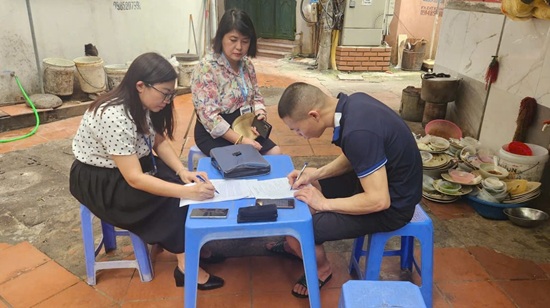 Lực lượng chức năng lập biên bản xử phạt quán cơm vi phạm an toàn thực phẩm và lấn chiếm ngõ đi. Ảnh: Phường Cầu Giấy