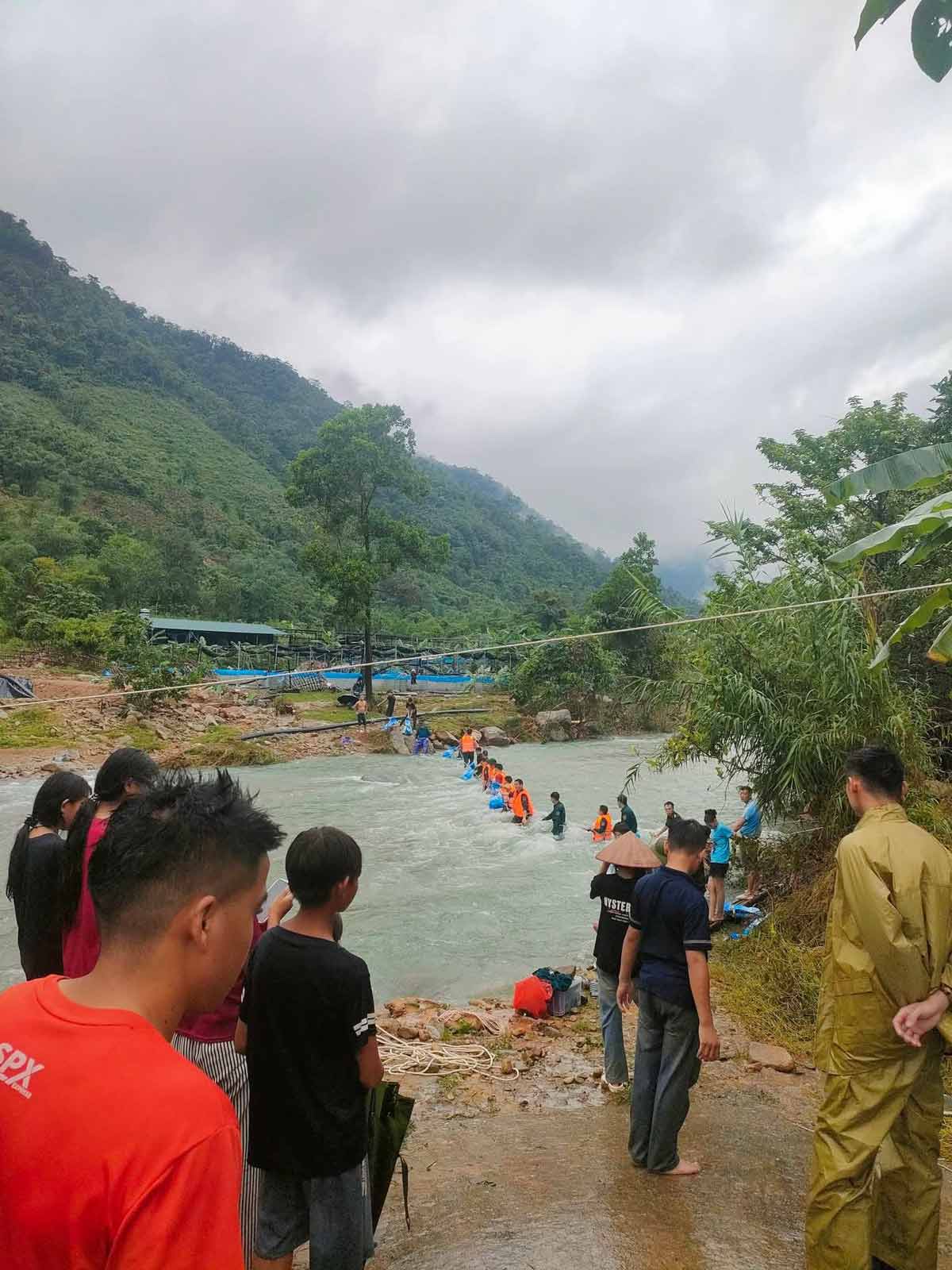 Do ảnh hưởng của mưa lớn, nước lũ tại sông dâng cao nên khiến khu vực nuôi cá tại bản Siệc Lống Mìn, xã Quảng Tân bị chia cắt, khó khăn trong giao thương, đi lại. Các lực lượng vũ trang và người dân đã thiết lập đội hình vận chuyển cá qua sông. Ảnh: UBMTTQ xã Quảng Tân