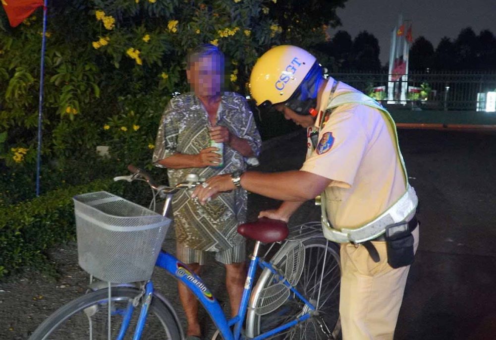 Un anciano que iba en bicicleta después de beber alcohol fue inspeccionado por la policía de tráfico y multado por violaciones de concentración de alcohol en la noche del 1 de mayo. Foto: Chan Phuc