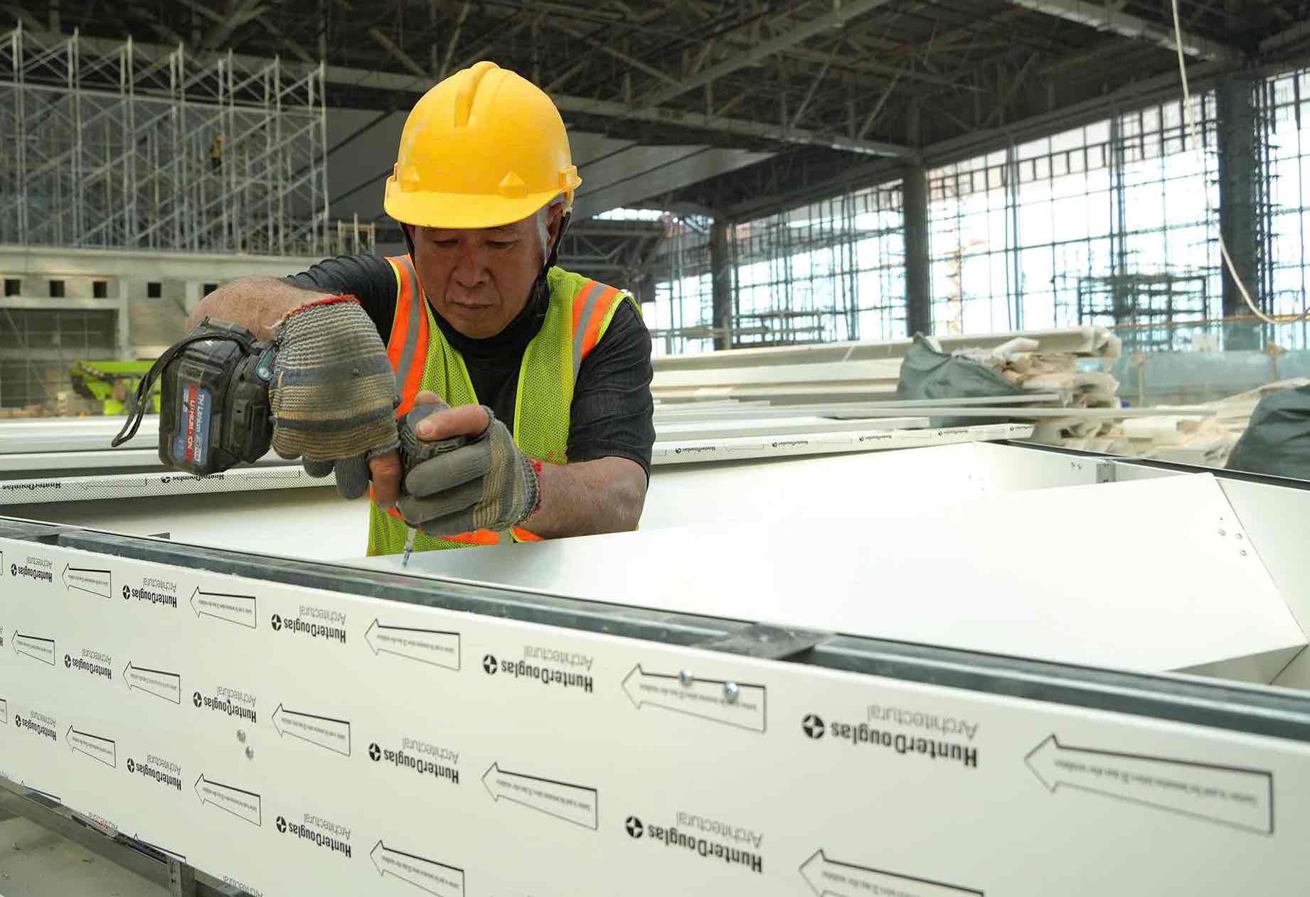 Người lao động thi công hoàn thiện các chi tiết phần mái nhà ga trước khi được lắp đặt. Ảnh: HAC