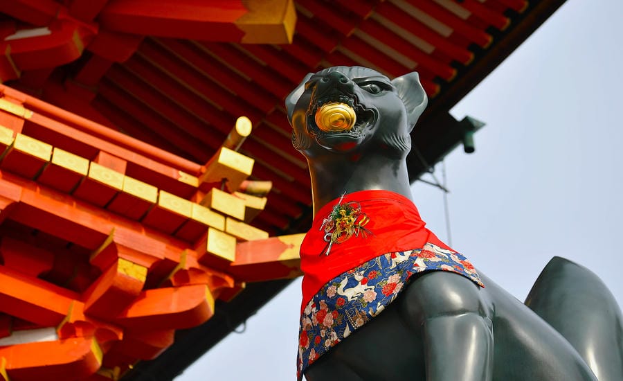 Tượng cáo - linh vật của thần Inari, đứng trước chính điện đỏ son tại Fushimi Inari Taisha. Trong tín ngưỡng Shinto, cáo được xem là sứ giả của vị thần bảo hộ mùa màng và thịnh vượng. Ảnh: Việt Văn
