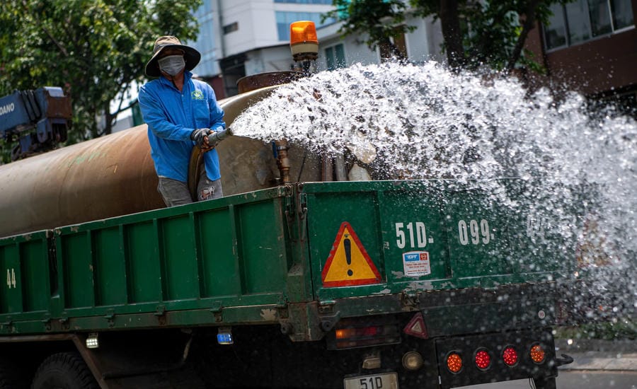 Công nhân công ty cây xanh tăng cường tưới nước dọc các tuyến phố nhằm chăm sóc cây trồng và góp phần làm dịu hơi nóng từ mặt đường nhựa. Ảnh: Anh Tú