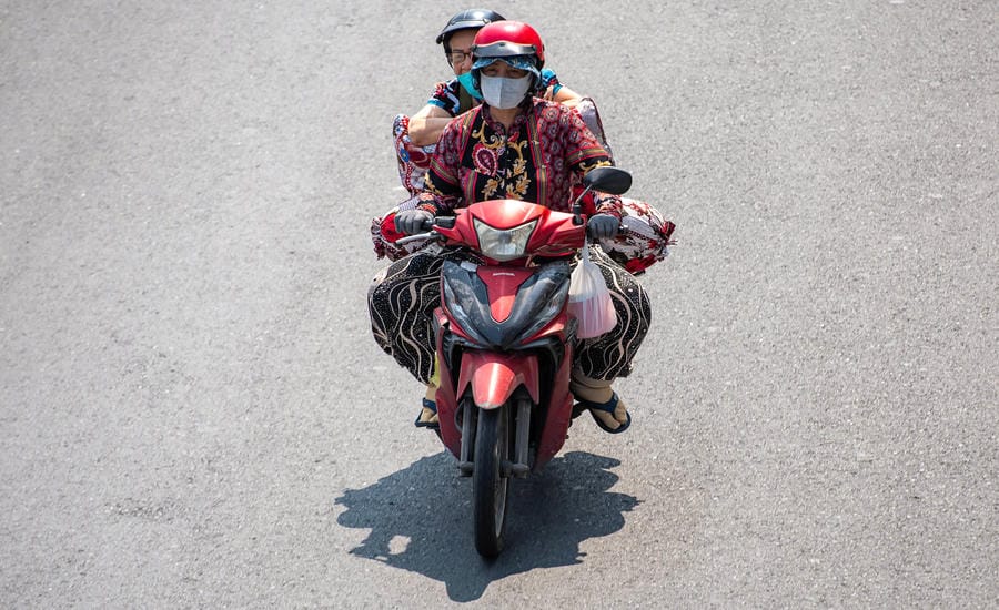Hơi nóng từ dưới mặt đường bủa vây, người dân ra đường phải bịt kín mít. Ảnh: Anh Tú