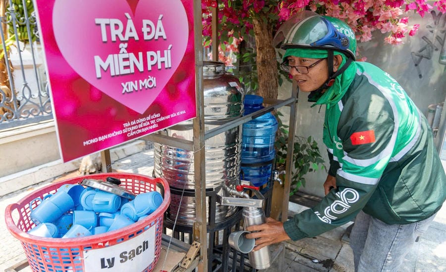 Giữa cái nắng oi ả, những bình trà đá miễn phí ven đường trở thành điểm dừng chân quen thuộc, góp phần xoa dịu cơn khát và lan tỏa tình người giữa phố thị đông đúc. Trên đường Hoàng Sa, một góc nhỏ trước nhà anh Dương Gia Hoàng đã trở thành “trạm nước” quen thuộc của nhiều người lao động suốt hơn một năm qua. Ảnh: Thái Bảo