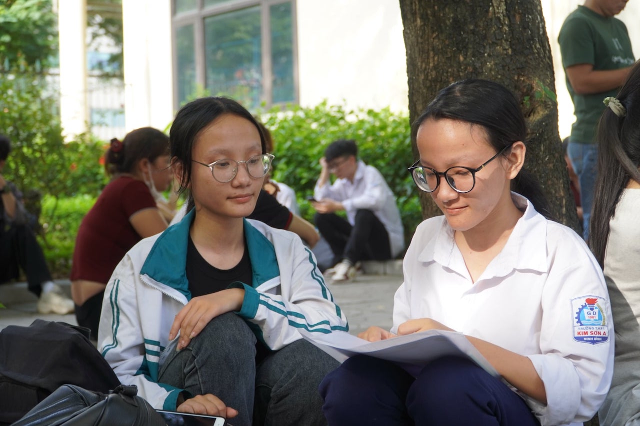 Trà My (tay phải) tranh thủ ôn lại bài trước giờ thi. Ảnh: Tường Vân