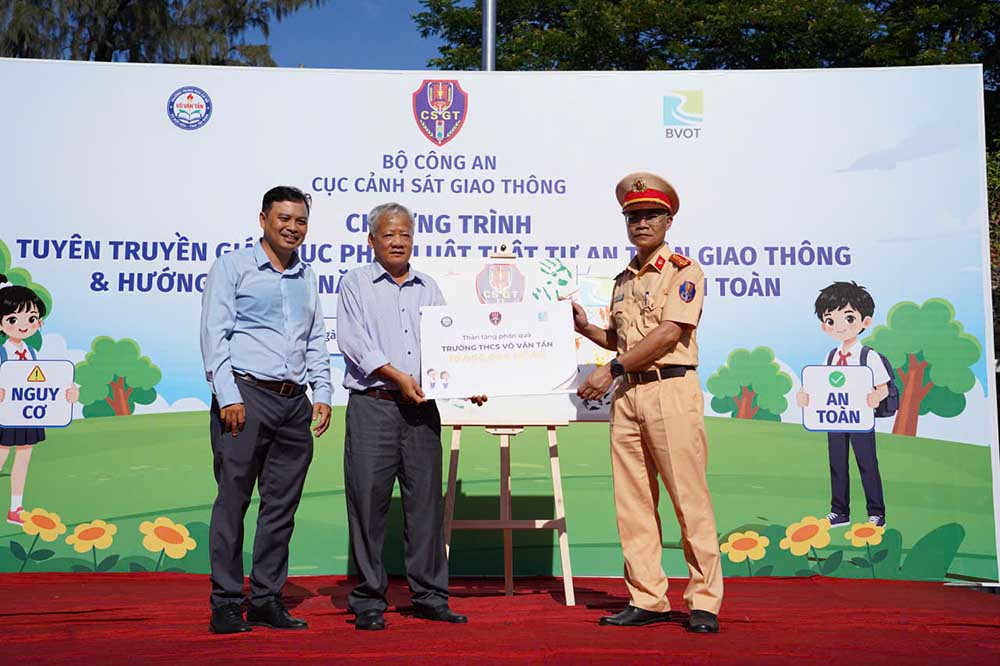 Ông Vũ Đình Vĩnh - Phó Trưởng phòng thuộc Cục Cảnh sát giao thông và ông Trần Hồng Ninh - Giám đốc Công ty TNHH BVOT Group trao quà tặng giáo dục cho đại diện Trường THCS Võ Văn Tần. Ảnh: Anh Vũ
