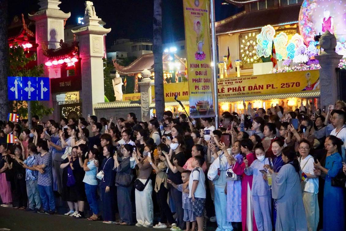 Rất đông người dân dõi theo đoàn rước kiệu hoa và tôn tượng Đức Phật ở hai bên đường. Ảnh: Mai Anh.