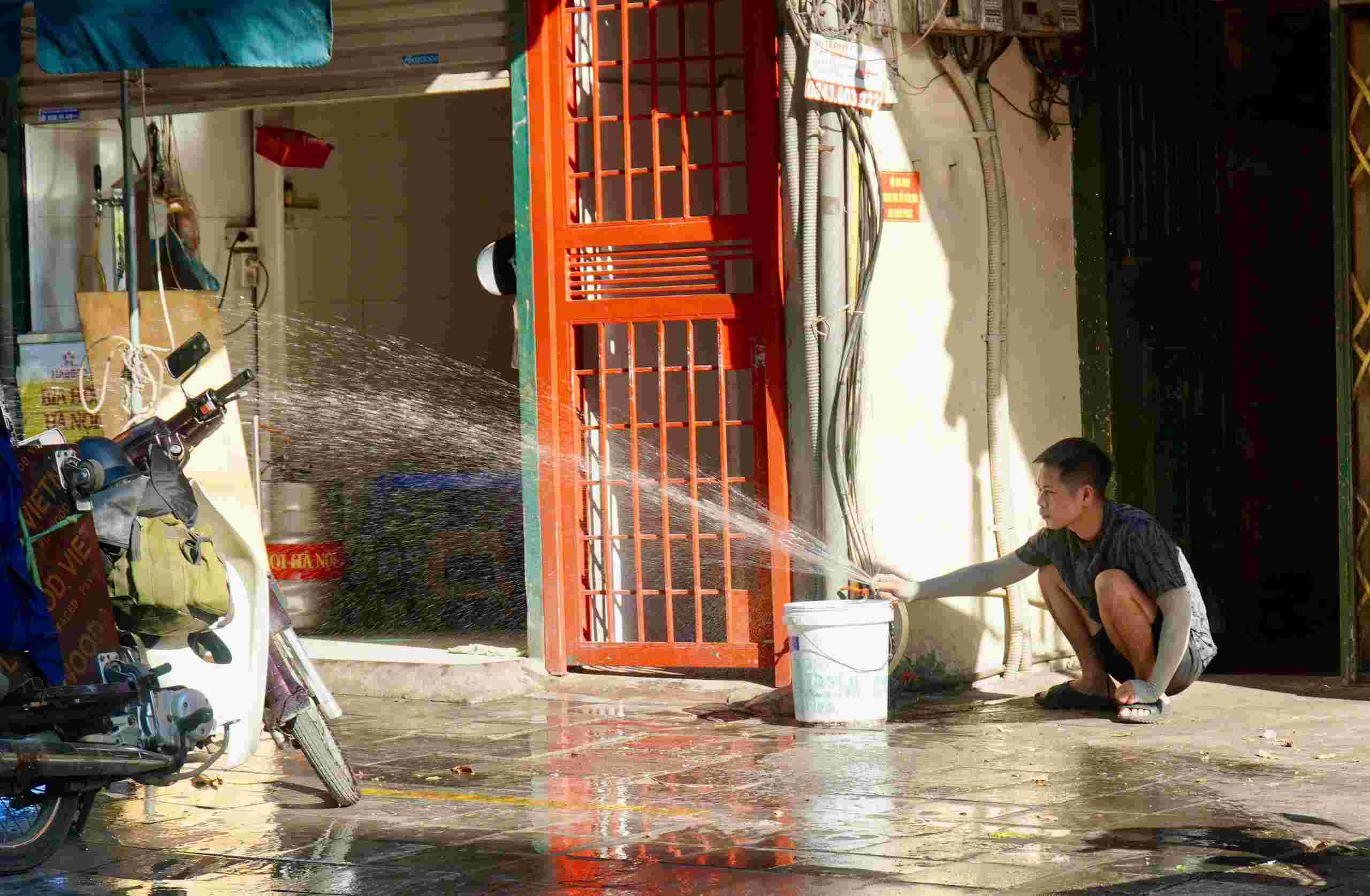 Nhiều gia đình sử dụng quạt, điều hòa, ngồi những chỗ râm mát, đổ nước ra đường và các biện pháp chống nóng để hạ nhiệt trong những ngày nắng gay gắt. Ảnh: Minh Vũ
