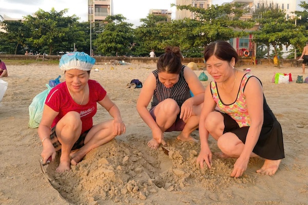 Với chiếc bay thợ xây, người dân nhanh chóng đào những hố cát cho mình. Ảnh: Ngọc Oanh