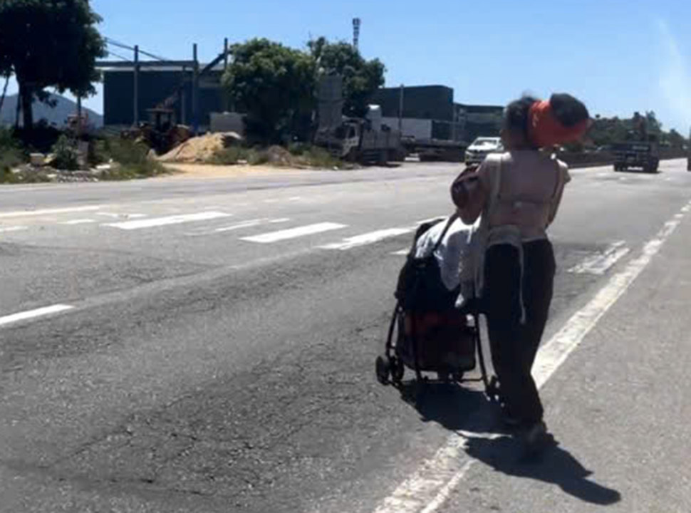 A mother takes her 2 young children walking on National Highway 1 through Ha Tinh province in 40-degree heat, causing public uproar. Photo cut from clip