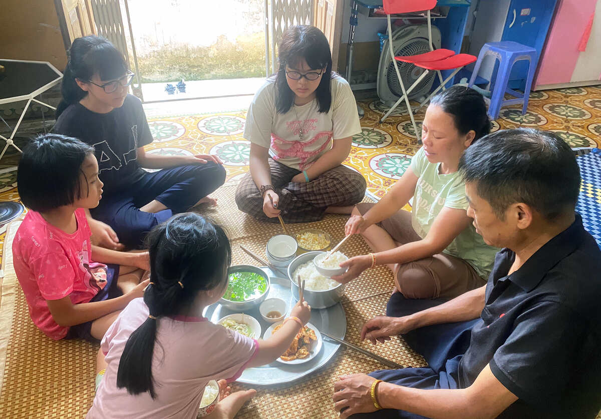 Cả nhà 6 người quây quần bên mâm cơm đạm bạc trong tiết trời nóng bức. Ảnh: Nguyễn Huệ