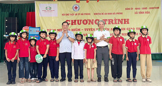 Representatives of local authorities and sponsors donate helmets to students of Vinh Hoa Primary School. Photo: Minh Chau