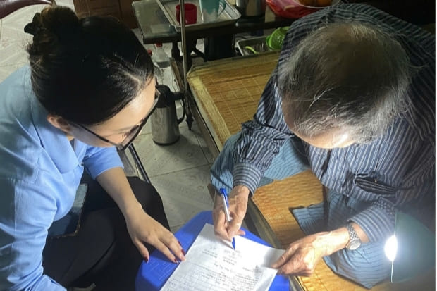 Cán bộ Chi nhánh số 3 hướng dẫn người cao tuổi làm giấy ủy quyền nhận lương hưu và trợ cấp BHXH hằng tháng tại nhà. Ảnh: Lê Trang