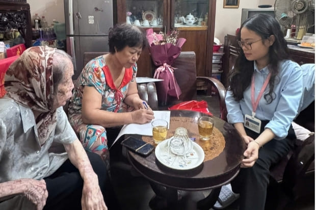 Cán bộ hướng dẫn người dân kê khai giấy tờ. Ảnh: Lê Trang