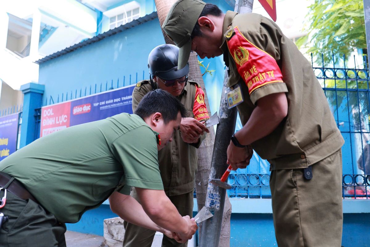 Các cột điện dán đầy quảng cáo rác, đang được lực lượng chức năng xóa bỏ. Ảnh: Minh Tâm